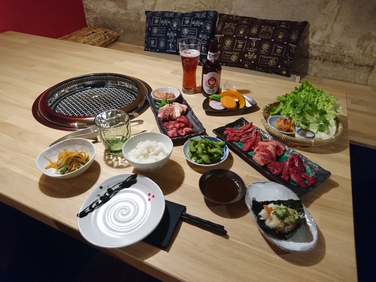 Une table de yakiniku dressée avec viandes, légumes, riz et condiments